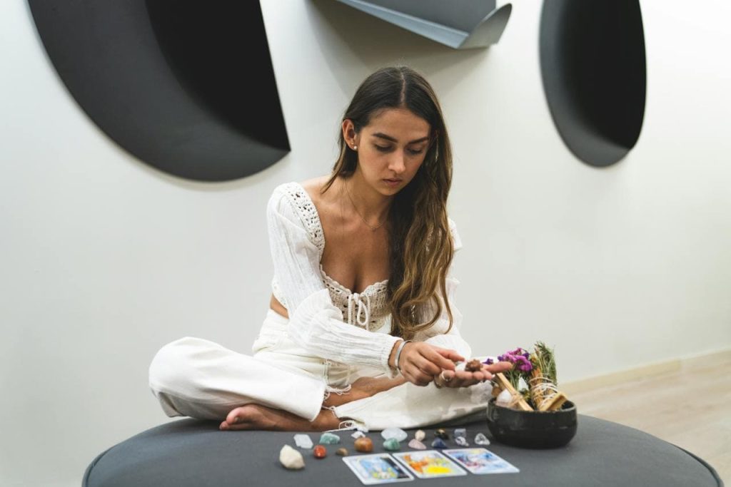 Mujer sentada en meditación con cartas de tarot y cristales, en un espacio tranquilo, representando la práctica personal y la introspección en la lectura del tarot.